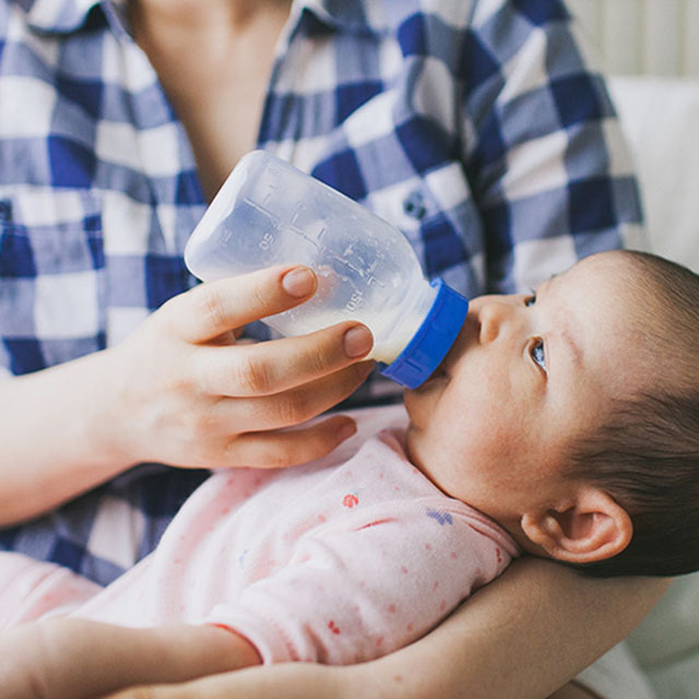 A mother feeds her infant a bottle of formula
