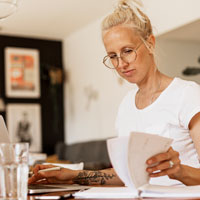 Woman works at a desk flipping through a calendar.