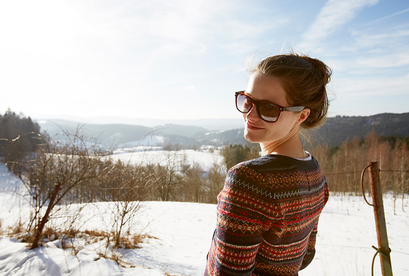 Woman standing in a snowy field wearing sunglasses