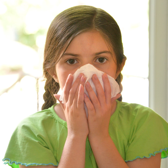 Girl blowing her nose into a tissue