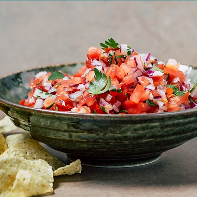 Bowl of tomato-based salsa with chopped cilantro garnish