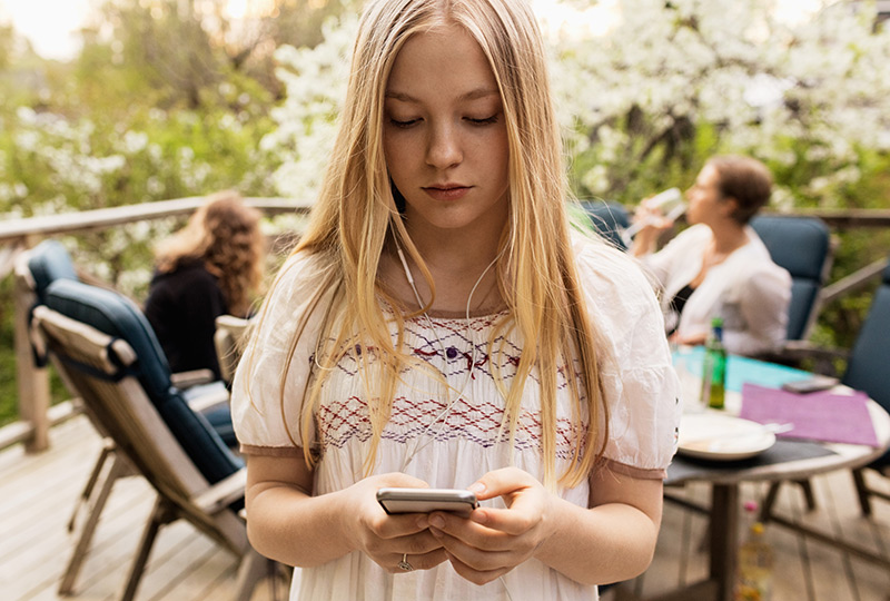 Teen girl looking at phone screen at family gathering.