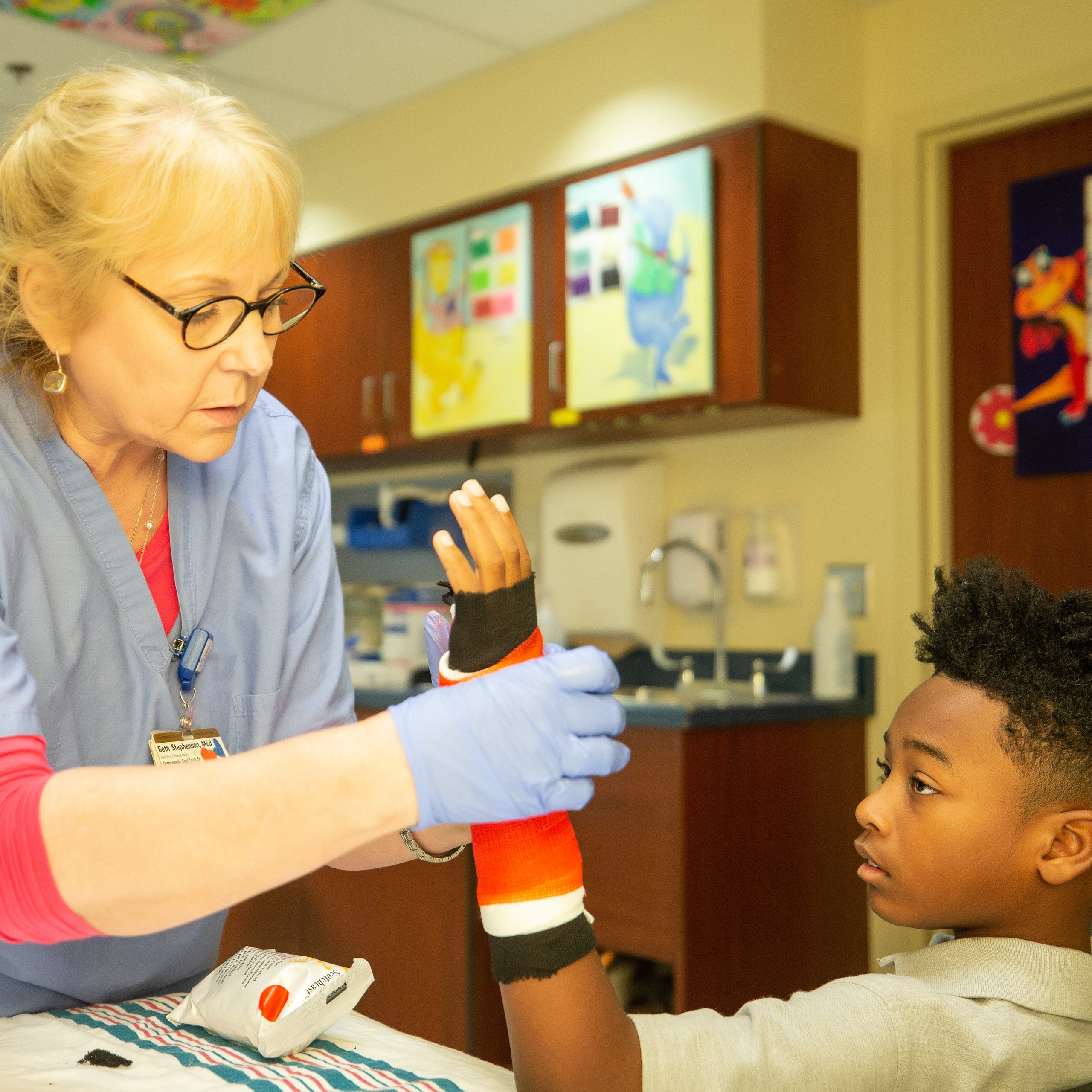 A nurse casts a boy's left arm