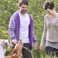 Man and woman playing with dog while on hike.