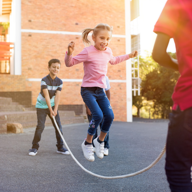 Children staying active and playing jumprope in playground