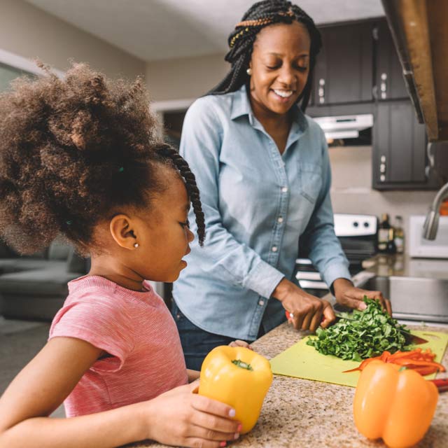 Mother and daughter cooking healthy meal and encouraging healthy living
