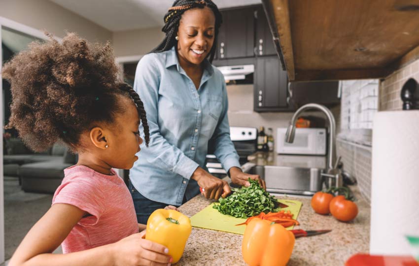 Mother and daughter cooking healthy meal and encouraging healthy living