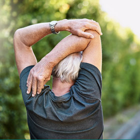 Older man, seen from behind, stretching his triceps.