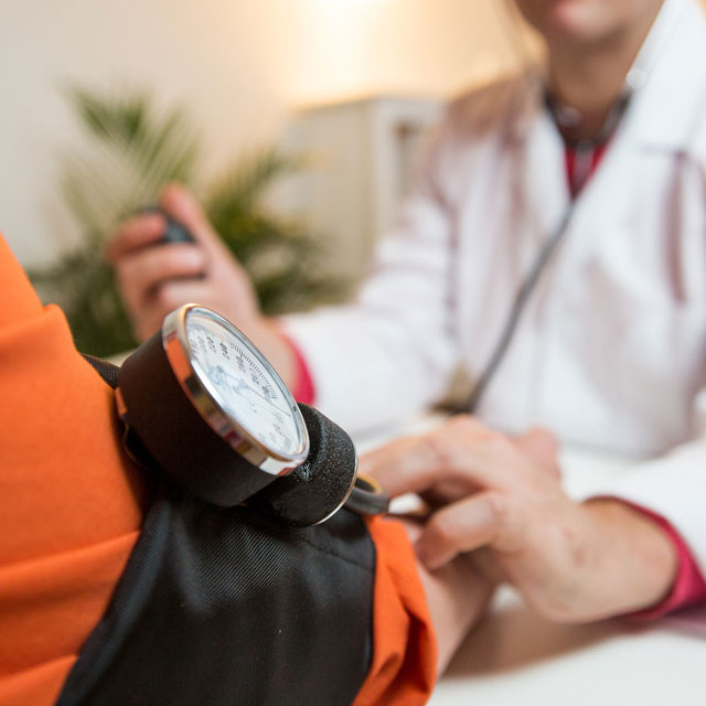 Nurse checking patient's blood pressure to catch early warning signs of stroke.