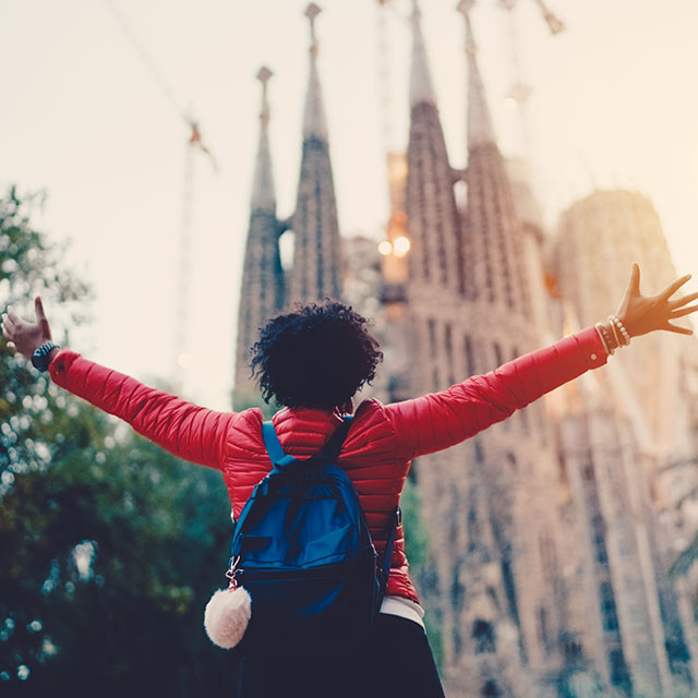 Following healthy travel tips can lead to happy travel experience like this woman posing in front of a cathedral in Spain.