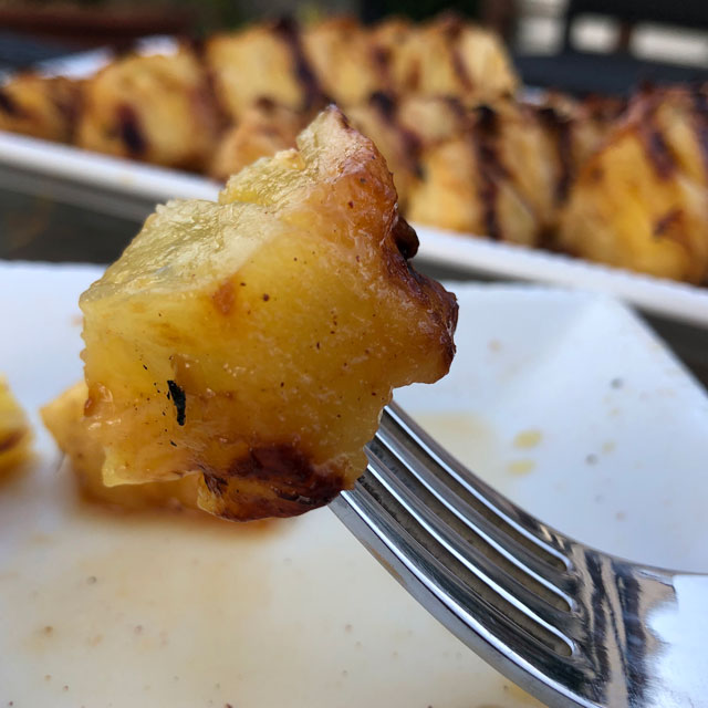 Closeup of a bit of grilled pineapple on a fork.