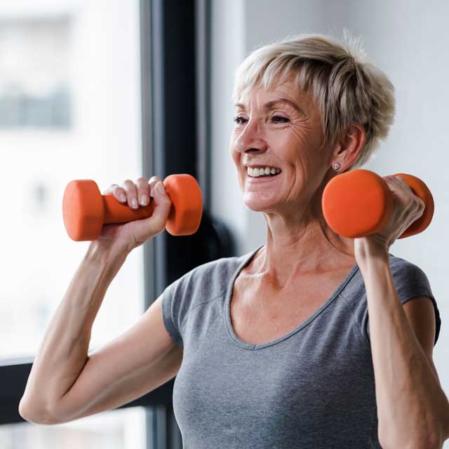 Woman reaping the benefits of strength training by working out with dumbbells.