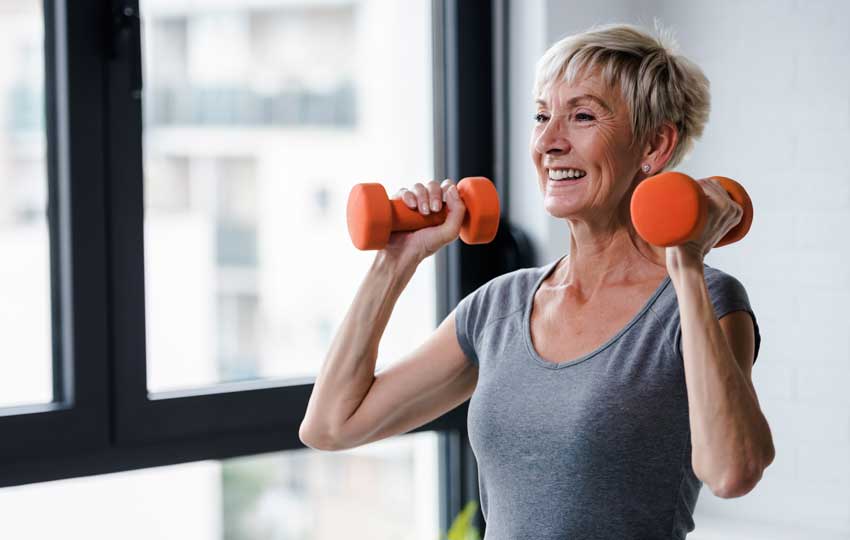 Woman reaping the benefits of strength training by working out with dumbbells.