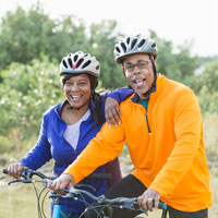 Small-size photo, a couple in bike helmets standing outdoors with their bikes.