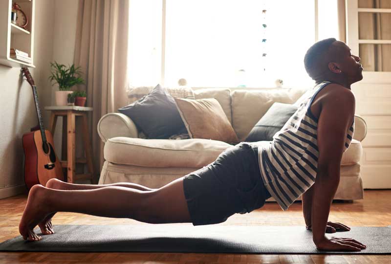 Man doing yoga at home as an exercise to reduce stress.