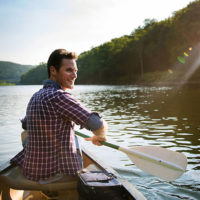 A man paddles a canoe on a river.