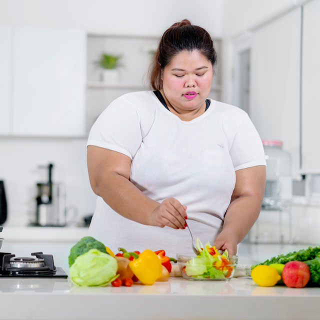 Heavyset woman prepares vegetables in a kitchen