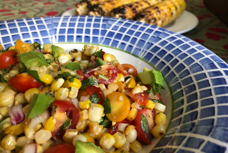 Closeup of grilled corn and tomato salsa in a blue serving bowl.