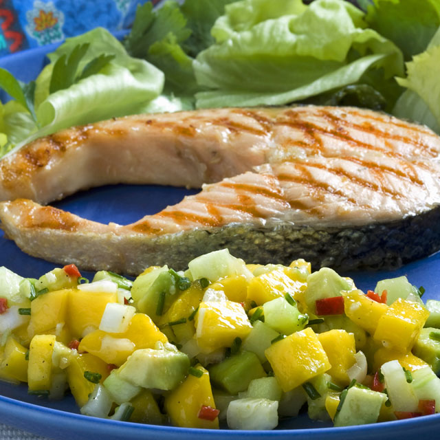 A grilled tuna steak plated with a mango-avocado salad on the side.