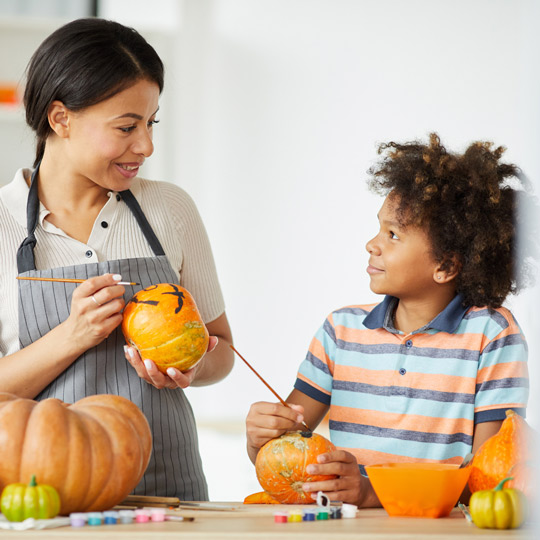 Woman painting pumpkins with child
