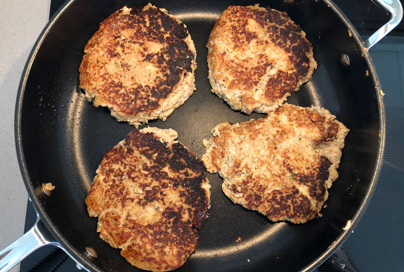 Homemade veggie burger patties cooking in a large skillet.