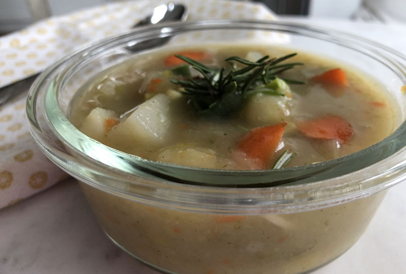 Homemade creamy potato leek soup served in a glass bowl.