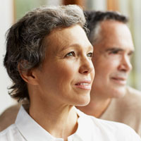 Middle aged couple in soft focus sitting next to each other looking away in the distance.