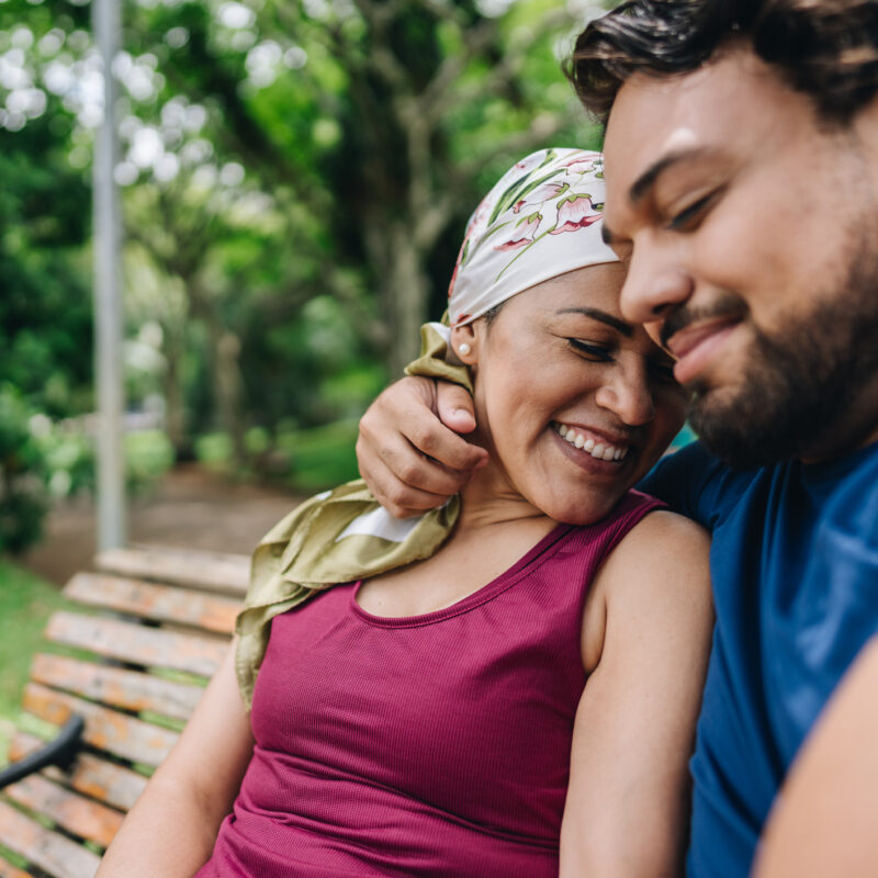 A mature woman who is battling brain tumor emotional changes embracing with her husband at park