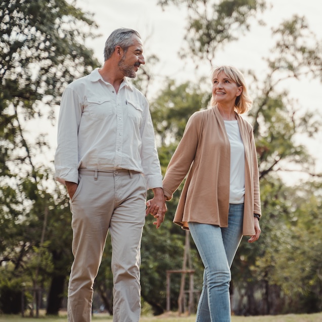 Senior active couple holding hands looks happy in the park in the afternoon autumn sunlight.