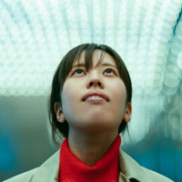 Closeup of young Asian woman looking up at a bank of lights indoors