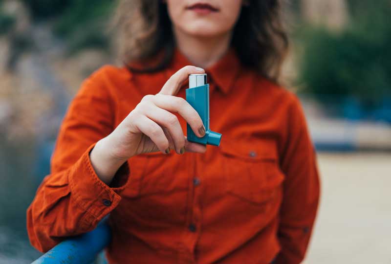 Woman with chronic asthma holding an inhaler