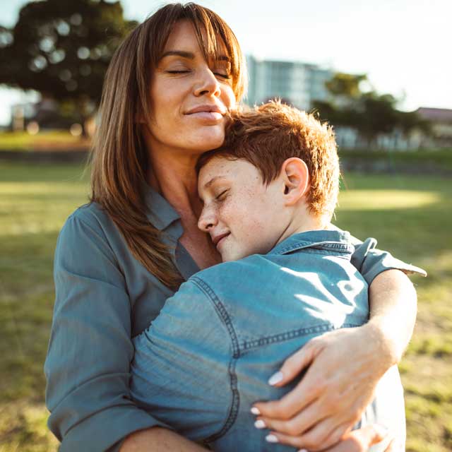 Close-up of a woman hugging a teenage child