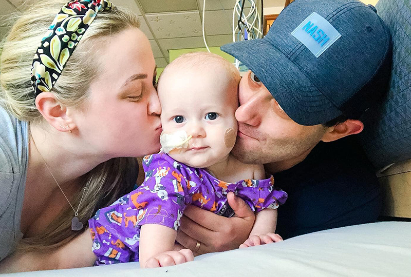 Mother and father kissing baby with in hospital recovering from RSV