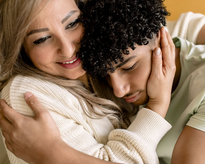 Closeup of a Latino woman embracing her teenaged son