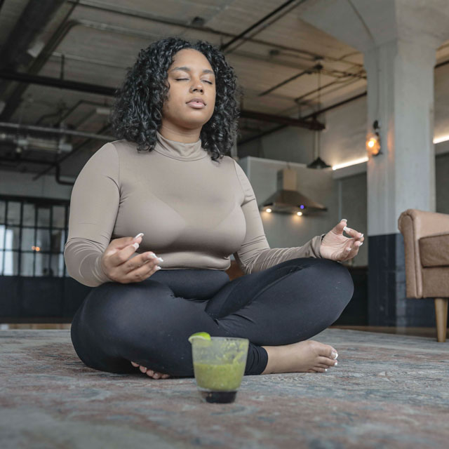 carpet in a large room, in a cross-legged yoga pose.