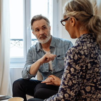 A middle aged couple facing each other look like they're having a difficult conversation.