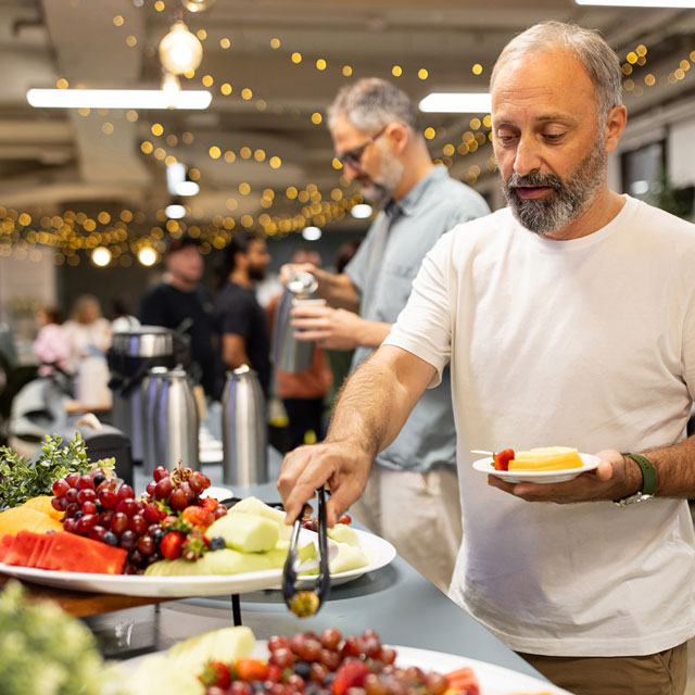 A man chooses fruit from a food buffet during a party.
