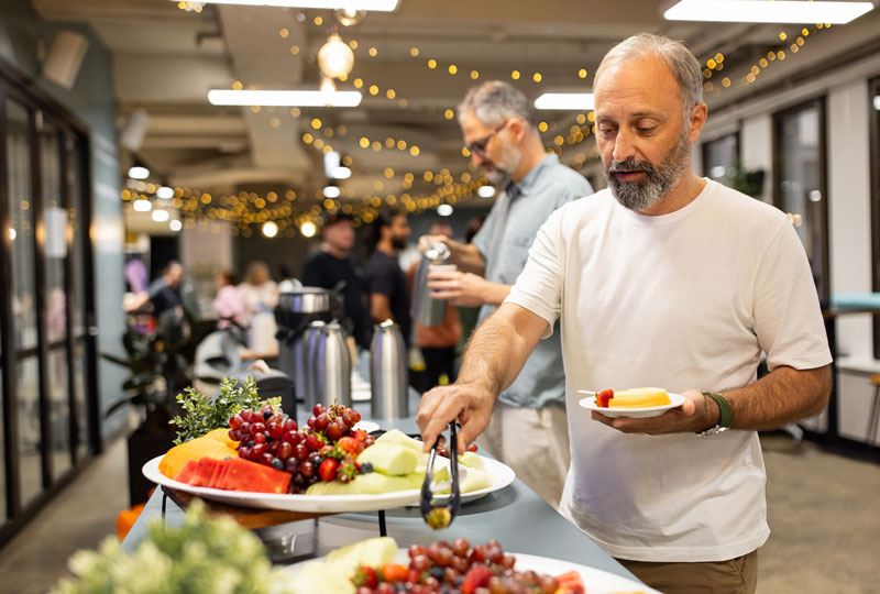 A man chooses fruit from a food buffet during a party.